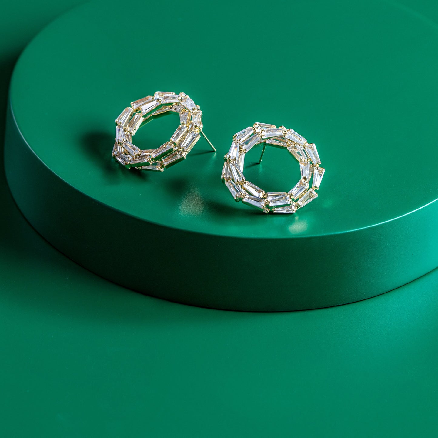 Pair of silver hoop earrings on a green platform