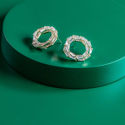 Pair of silver hoop earrings on a green platform
