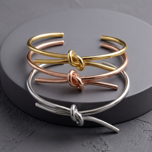 Woman wearing stacked gold and silver knot cuff bracelets on her wrist while holding a ceramic mug — minimalist jewellery by Rock Paper Scissors