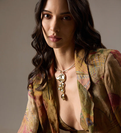 Woman wearing a patterned jacket and a stunning gold drip statement necklace 