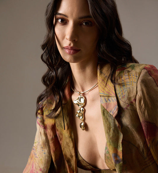 Woman wearing a patterned jacket and a stunning gold drip statement necklace 