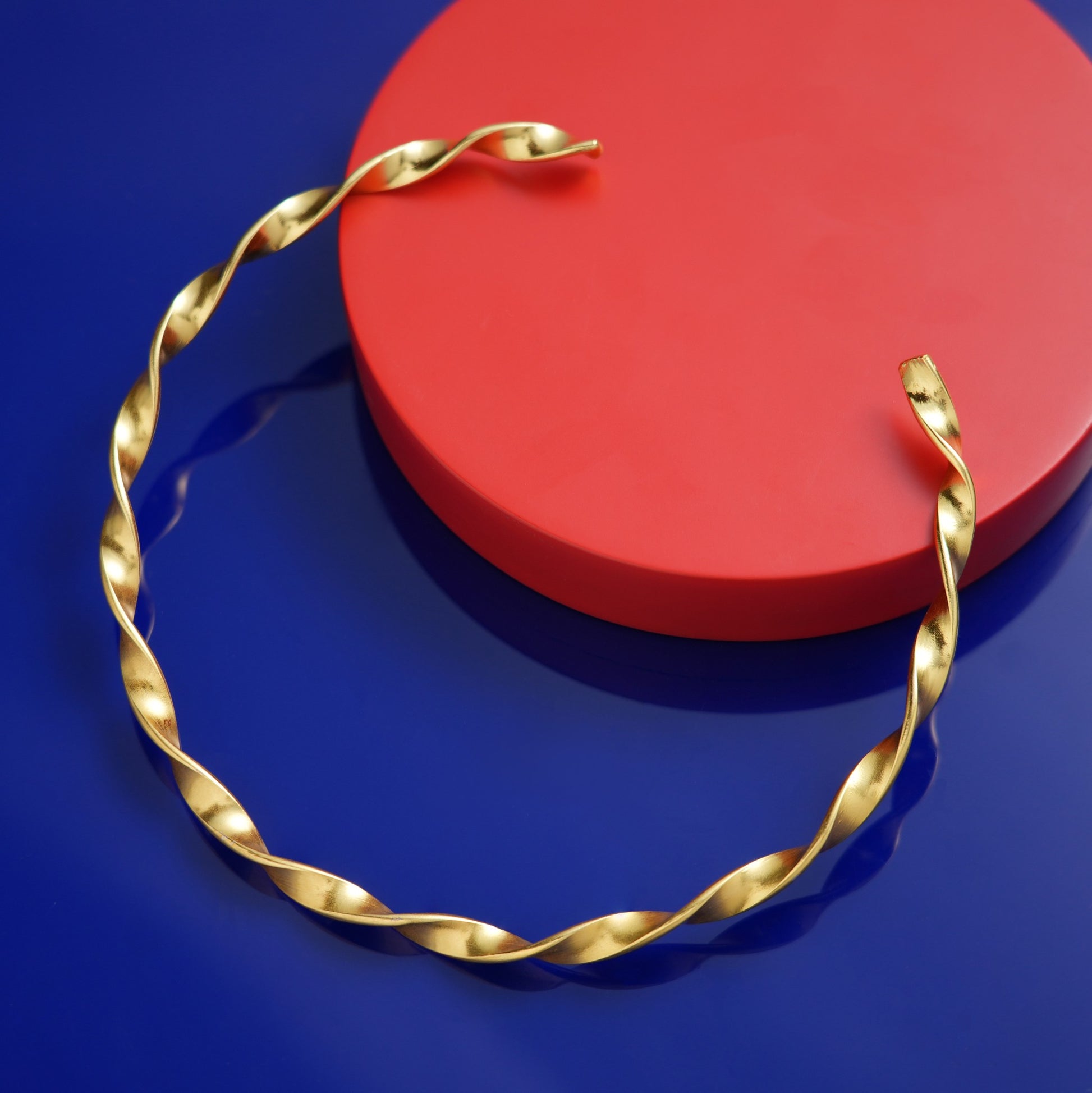 stiff Gold necklace on a blue and red background